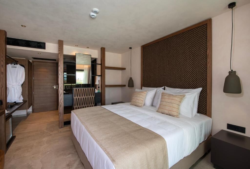 Et moderne hotelværelse med en stor seng, et træhovedgærde, et sengebord og et skab.