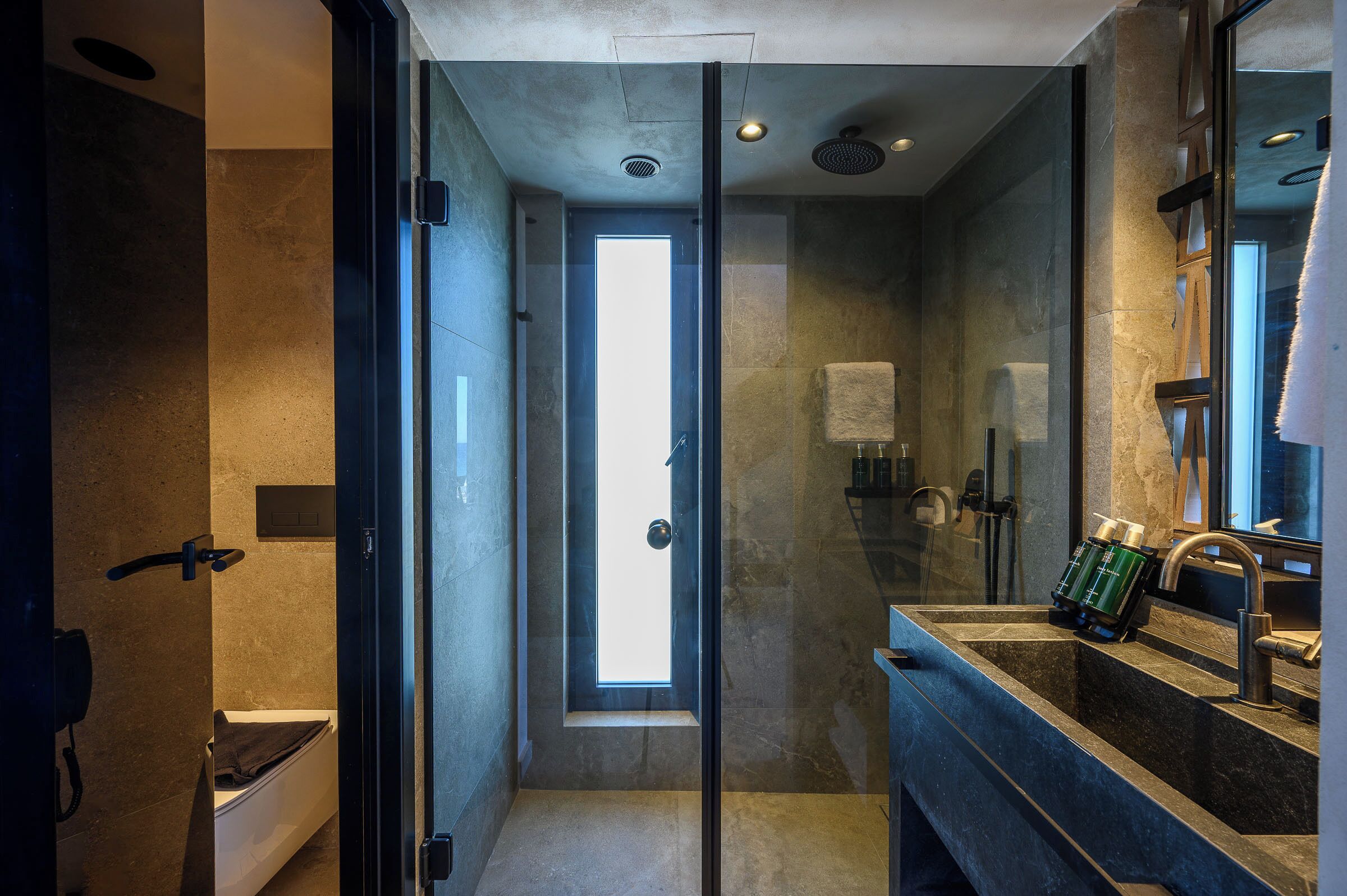 A modern bathroom with a glass shower enclosure, a large mirror, and a built-in sink.