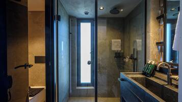 A modern bathroom with a glass shower enclosure, a large mirror, and a built-in sink.