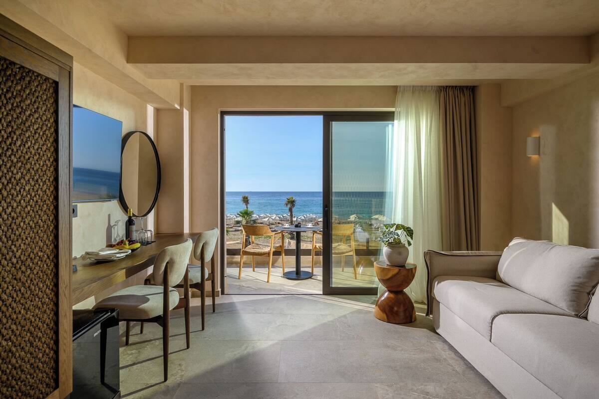 Une chambre d’hôtel avec un balcon, un coin repas et un canapé.