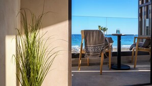 Ein Balkon mit Meerblick, einer Küstertopf-Pflanze und zwei Stühlen mit einem Tisch.