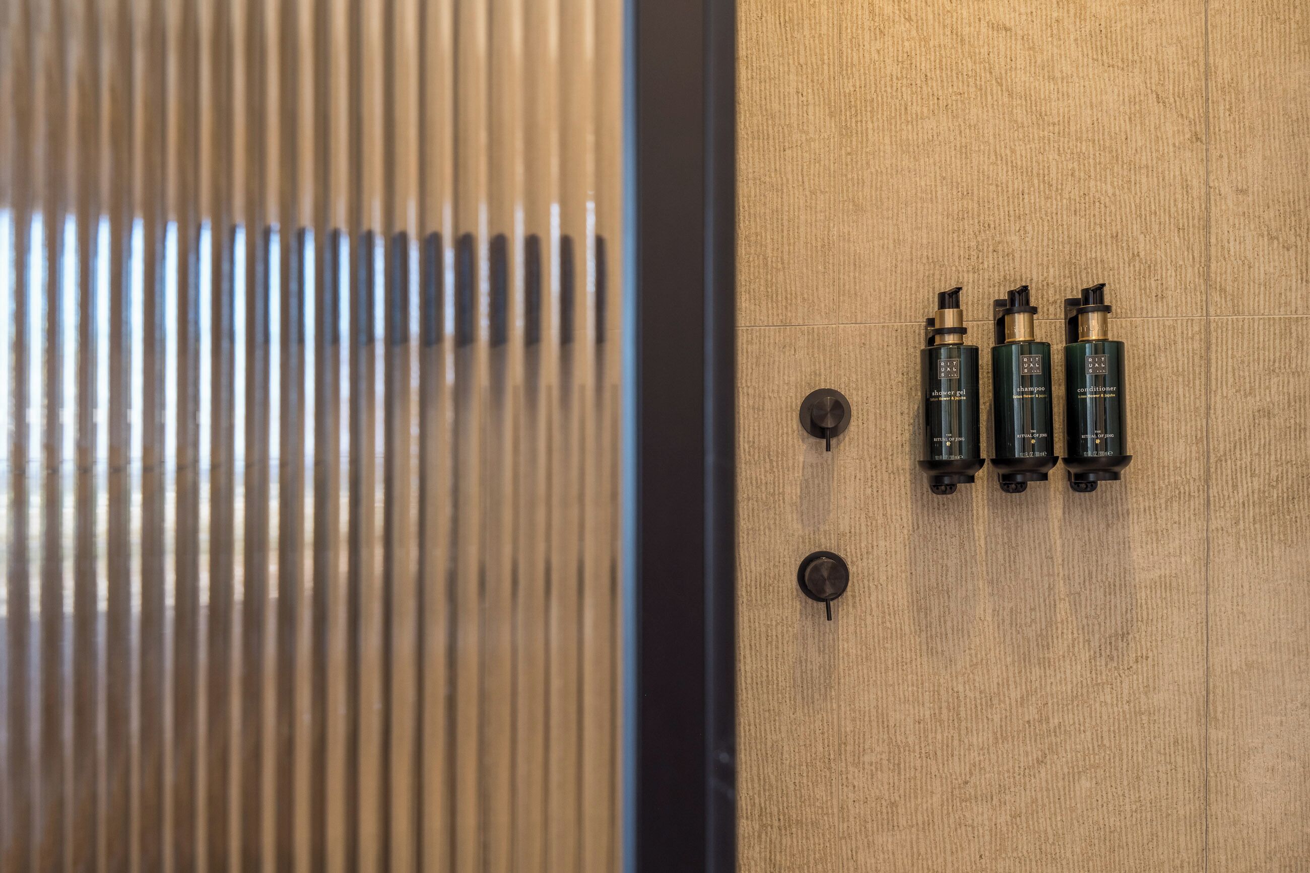 Une porte en bois avec trois bouteilles de shampoing noires et une poignée en métal.