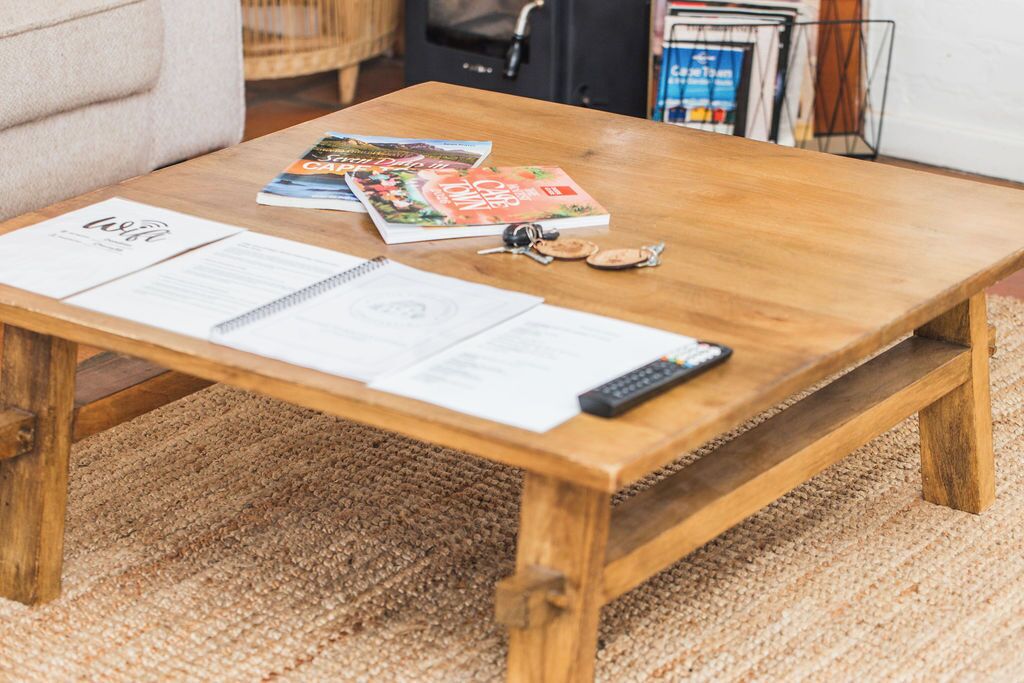 A wooden coffee table with magazines, keys, and a remote control.