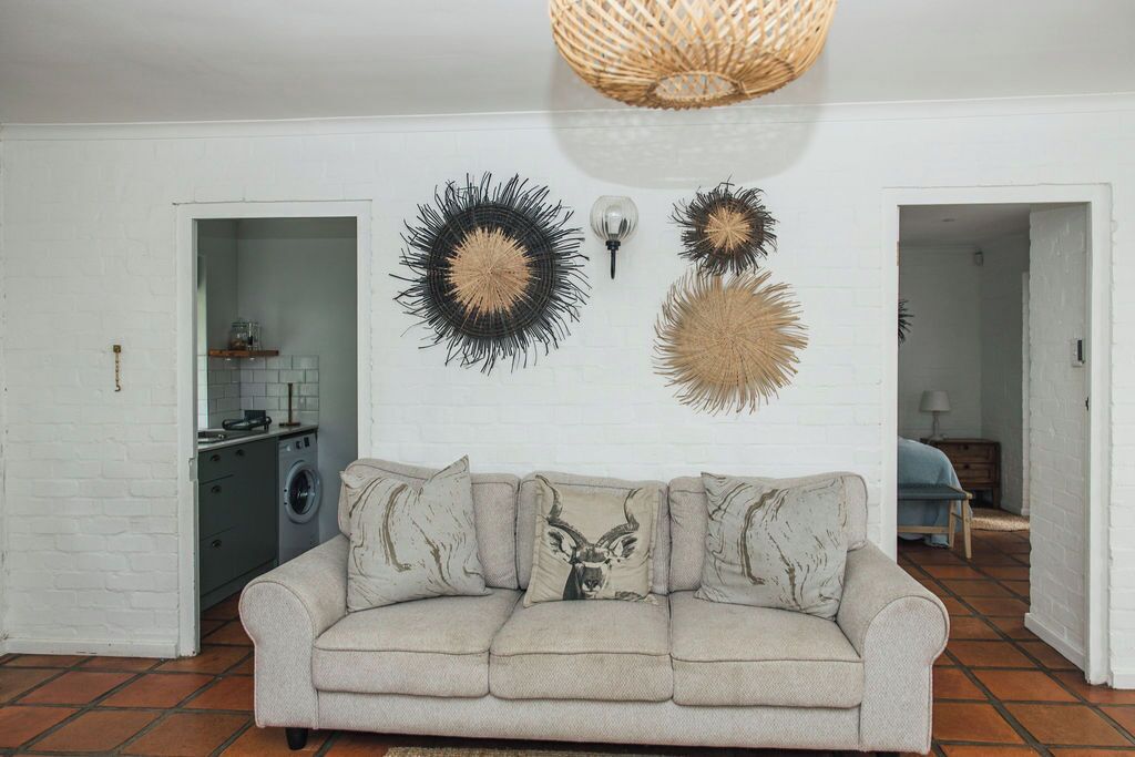 A living room with a sofa, a kitchen in the background, and decorative wall art.