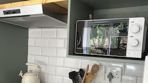 Une cuisine équipée d’une cuisinière à gaz, d’une bouilloire, d’un grille-pain et d’un four à micro-ondes.