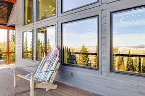 A modern building with large windows and a deck area with a chair and magazines.