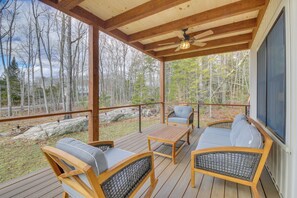 A covered deck with wooden furniture, a ceiling fan, and a view of a forested area. - 4 Mi to Boothbay Harbor: Quiet Retreat w/ Deck (Boothbay)