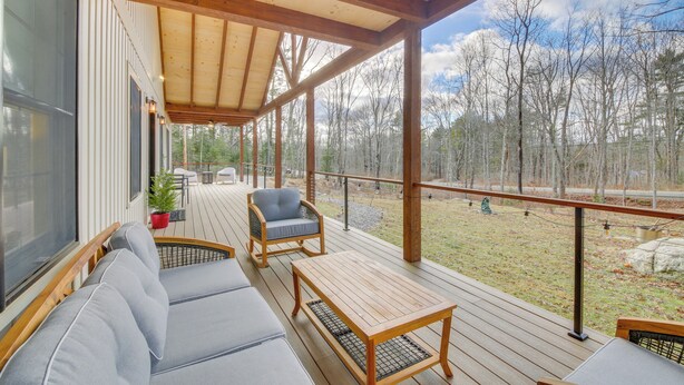 Une terrasse extérieure couverte, aménagée avec un canapé, des fauteuils et une table.