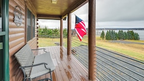 En træhytte med veranda, bænk og et amerikansk flag.