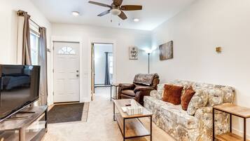 A living room with a television, sofa, coffee table, and a ceiling fan.