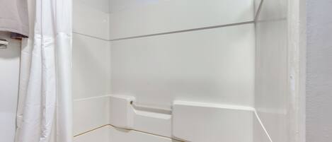 A bathroom with a bathtub, a shower curtain, and a white tiled wall.