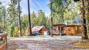 A rustic cabin with a gravel driveway, surrounded by tall pine trees. - Walk to Golf, Lake: Twain Harte Cabin w/ Fireplace (Twain Harte)