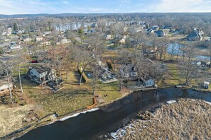 An aerial view of a residential area with houses, a river, and a bridge.