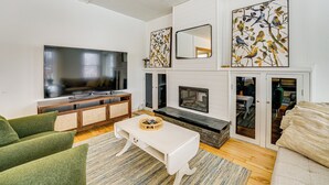 Ein modernes Wohnzimmer mit Flachbildfernseher, Kamin und Kunstwerken an den Wänden.