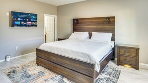 A bedroom with a wooden bed, a TV mounted on the wall, a ceiling fan, and a nightstand with drawers. - 3 Mi to Tucson Mall: Home w/ Large Outdoor Space! (Tucson)