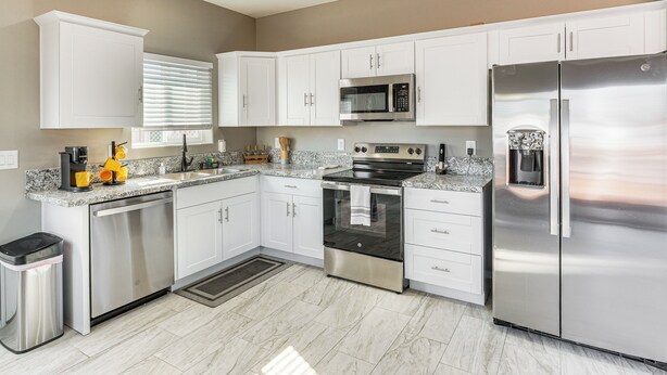 A modern kitchen with white cabinets, stainless steel appliances, and a granite countertop. - 3 Mi to Tucson Mall: Home w/ Large Outdoor Space! (Tucson)
