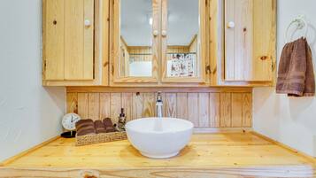 Un tocador de madera con un lavabo blanco grande, armarios de madera y un espejo.