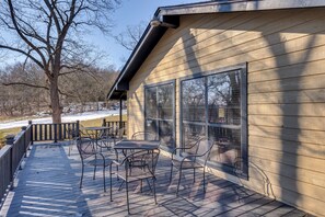 A wooden deck with metal chairs and a table, overlooking a snowy landscape.