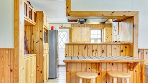 Une cuisine en bois avec un coin bar, des meubles de rangement en bois et un réfrigérateur.