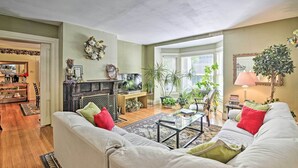 A living room with a fireplace, sofa, coffee table, and various plants. - Walk to Keuka Lake! Fun, Spacious Retreat w/ Pool (Hammondsport)
