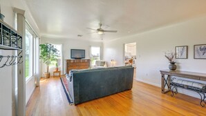 A spacious living room with hardwood flooring, a large grey sofa, a ceiling fan, and a television on the wall. - 19 Mi to Sequoia Natl Park: Mtn-view Woodlake Gem (Woodlake)