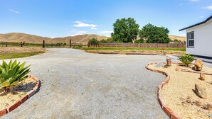 A paved driveway leading to a white building with a fenced area containing plants and rocks. - 19 Mi to Sequoia Natl Park: Mtn-view Woodlake Gem (Woodlake)
