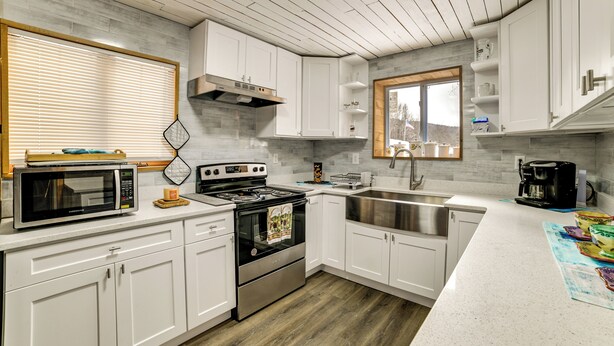Una cocina moderna con armarios blancos, electrodomésticos de acero inoxidable y techo de madera.
