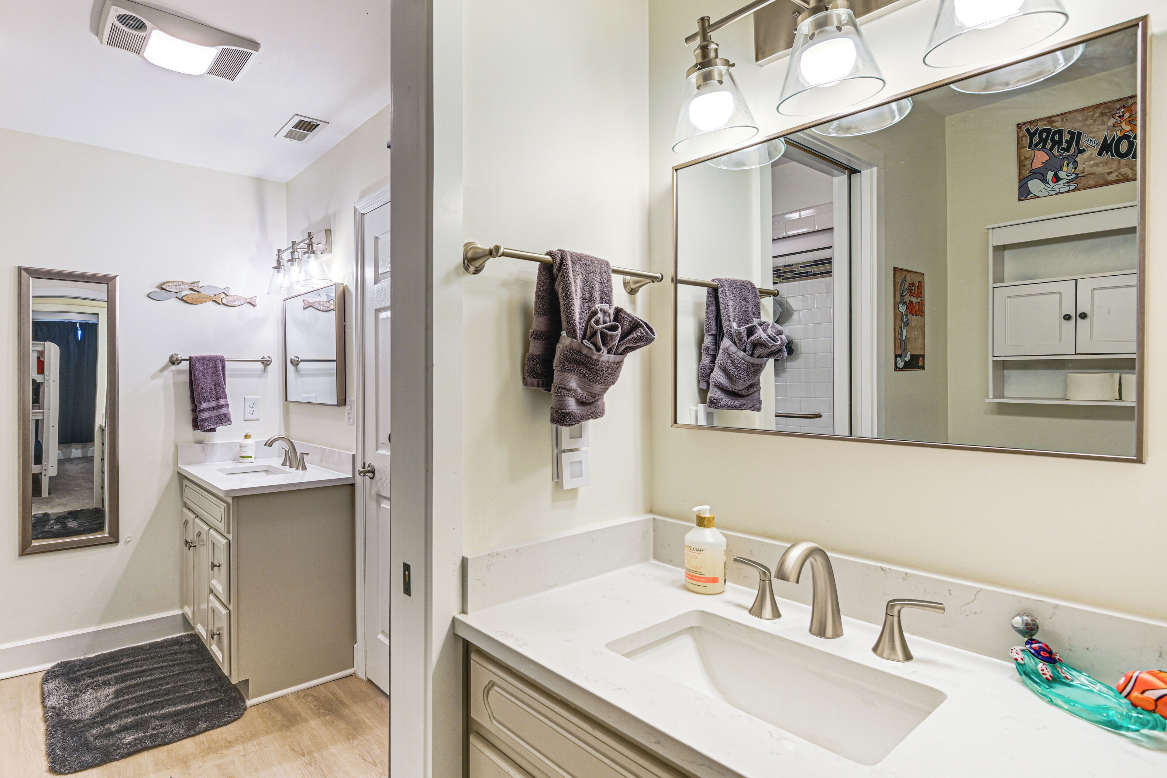 A bathroom with a sink, mirror, towel rack, and a small shelf with toiletries.