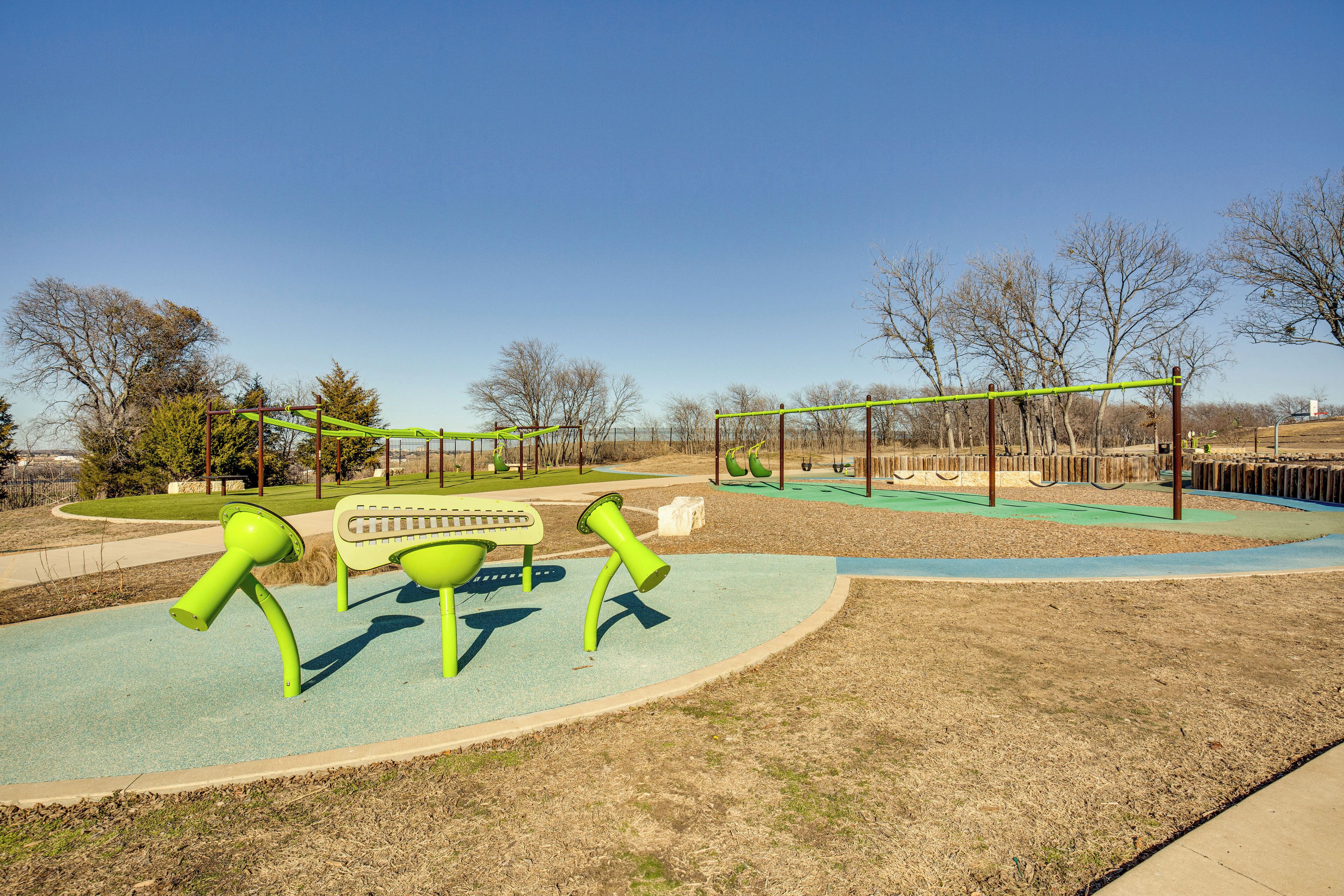 A playground with green equipment, a bench, and a fenced area.
