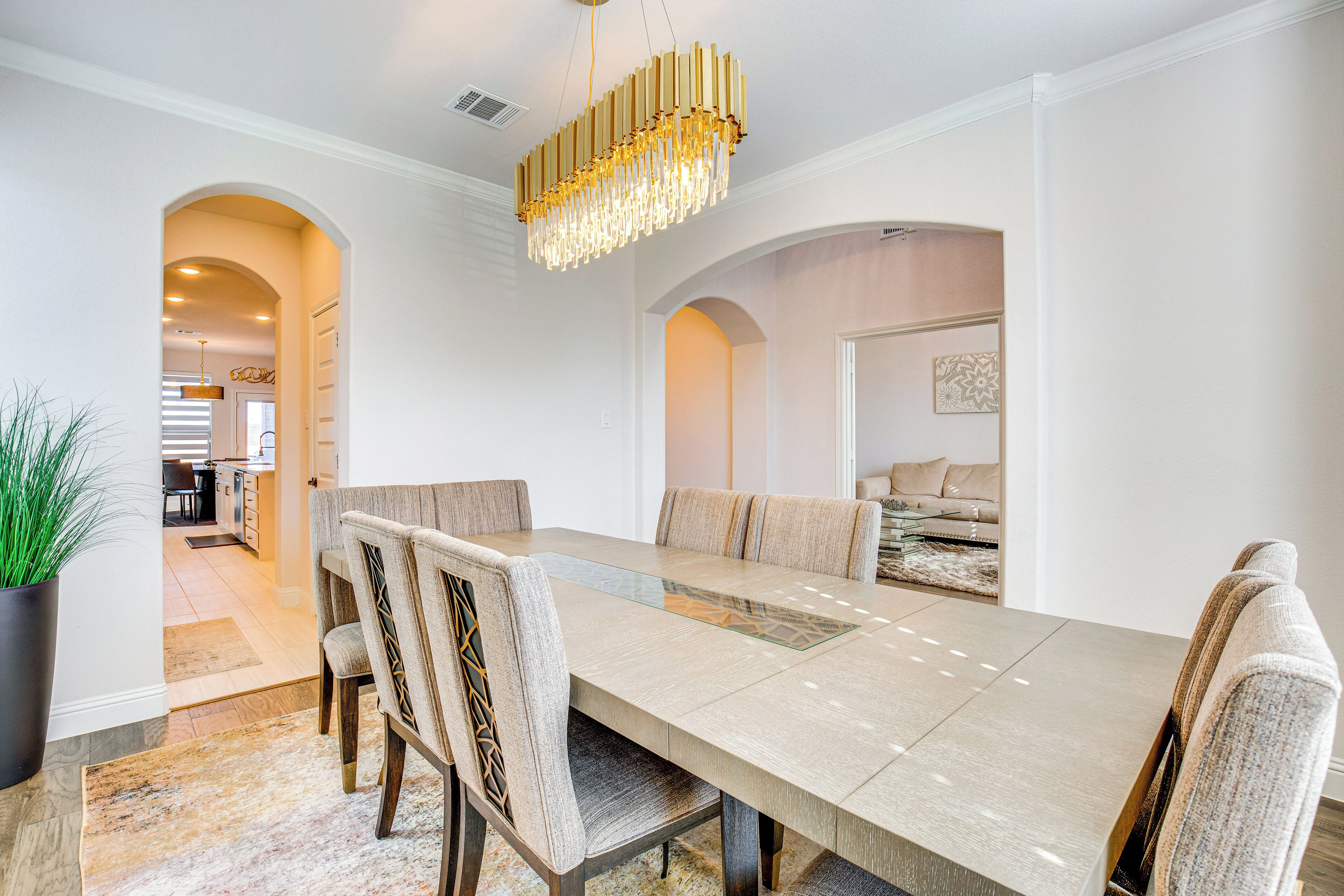 Une salle à manger moderne avec une longue table, des chaises confortables et un lustre décoratif.