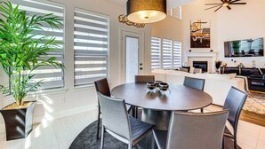 A modern dining area with a round table, chairs, and a hanging light fixture. - 6 Mi to Lake Lewisville: Chic Retreat in Frisco! (Frisco)