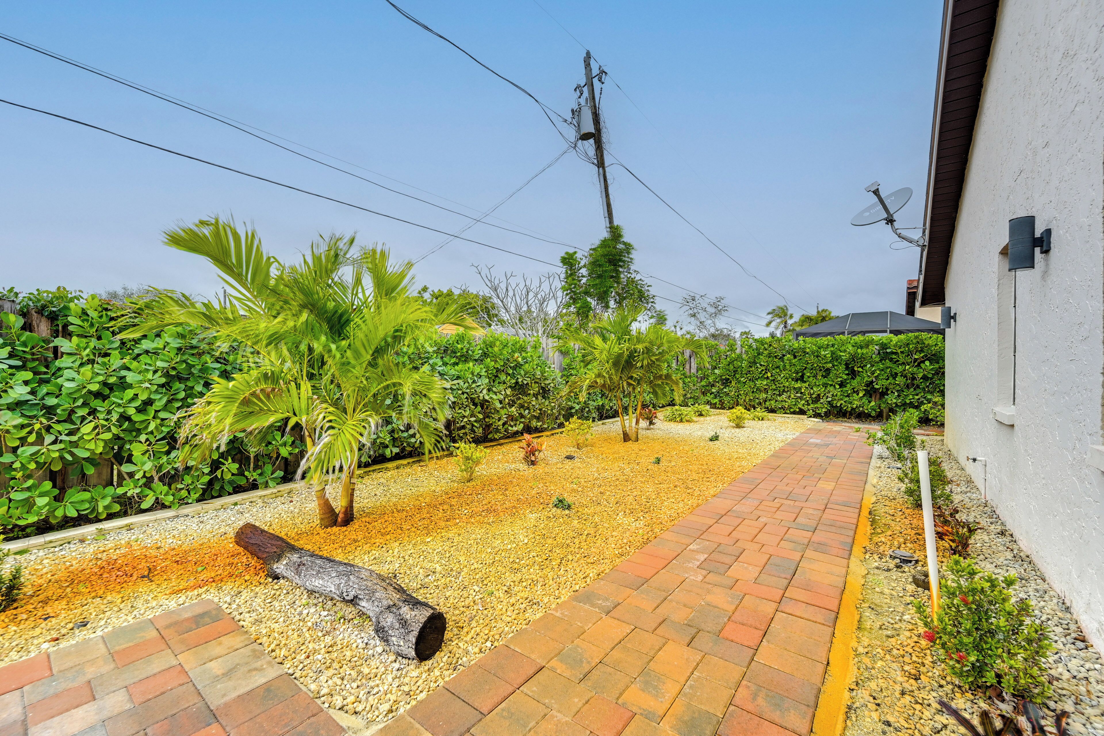 A garden with a gravel path, palm trees, and a white building.