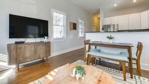 A modern living room with a flat-screen TV, wooden cabinet, dining table, and chairs. - 1 Mi to Dtwn: Home w/ Backyard in Raleigh! (Raleigh)