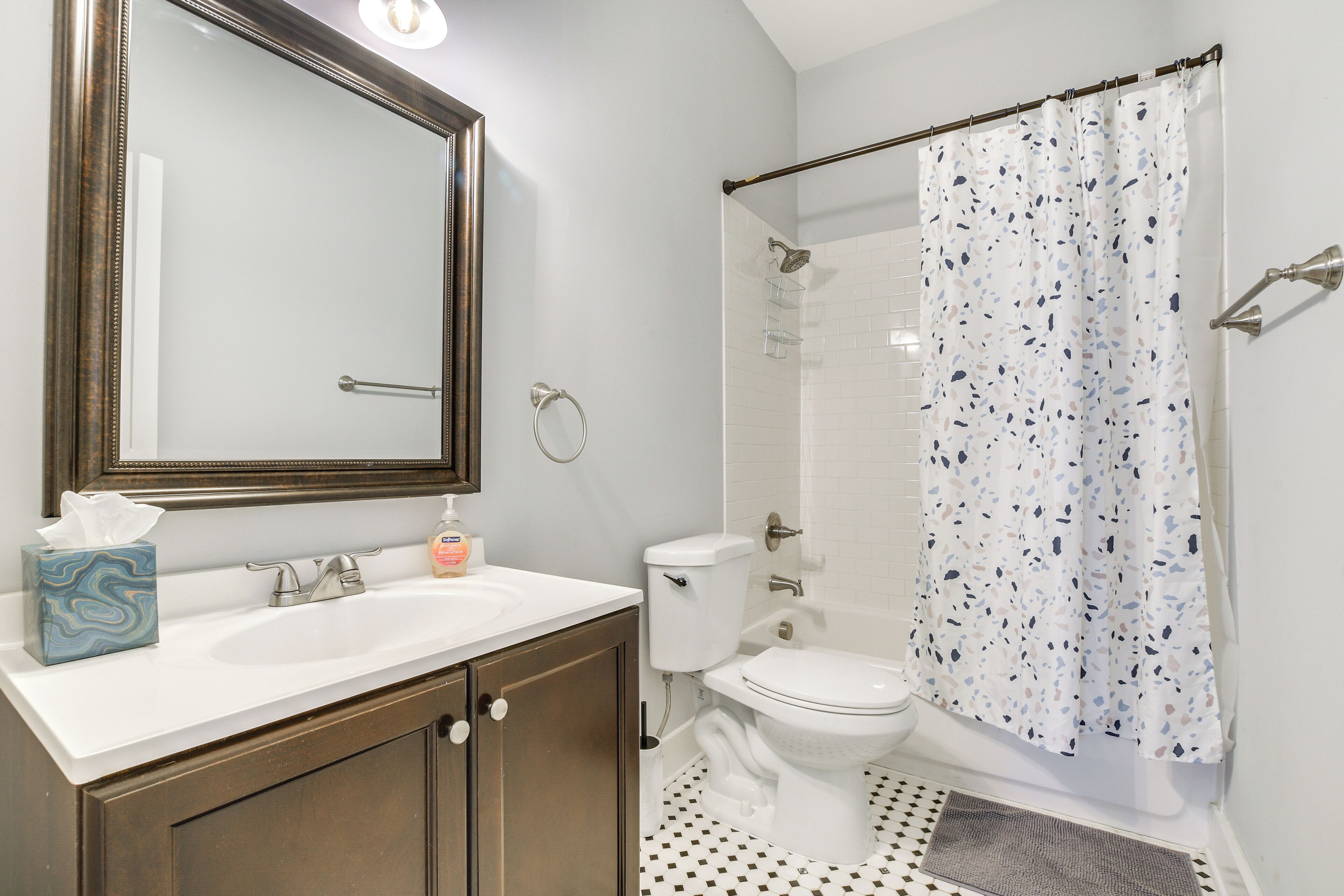A bathroom with a white sink, a mirror, a toilet, and a shower curtain.