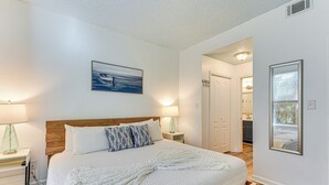Ein Schlafzimmer mit einem großen Bett, einem Holzkopfteil, weißer Bettwäsche und einem Gemälde darüber.