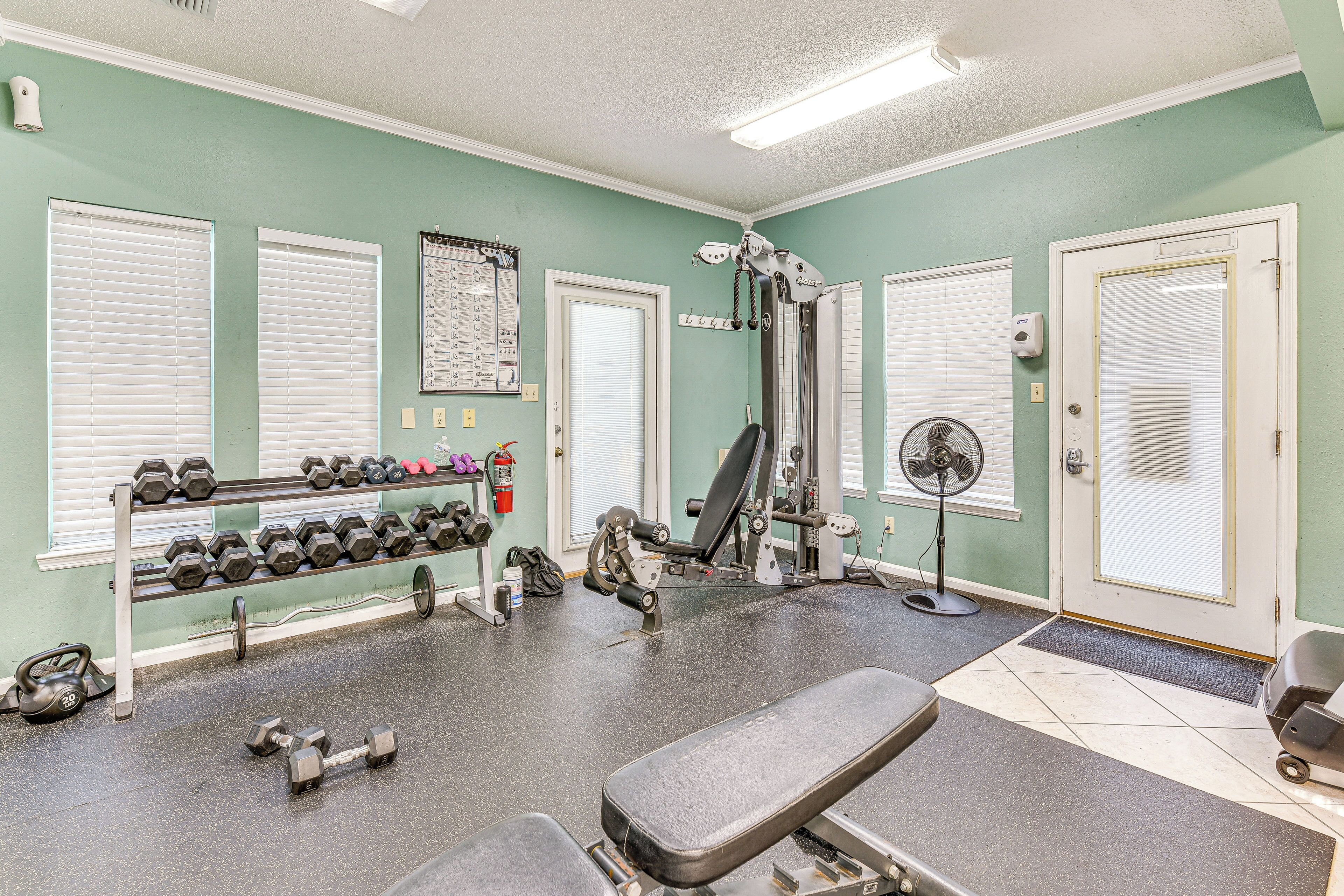 A gym with exercise equipment, dumbbells, and a bench.