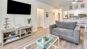 Ein modernes Wohnzimmer mit einem grauen Sofa, einem Flachbildfernseher, einem Couchtisch und einem Bücherregal.