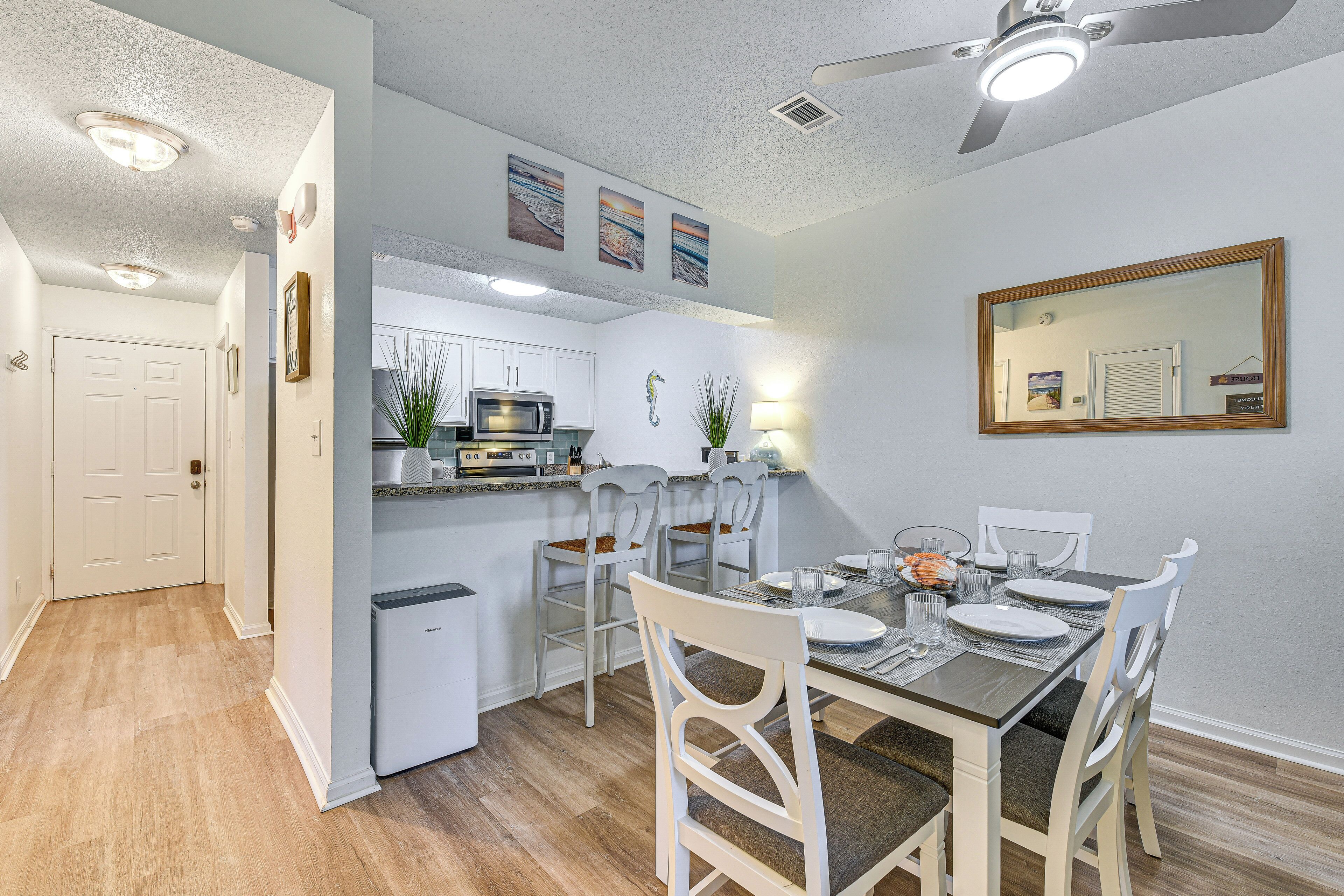 A modern kitchen with white cabinets, a microwave, and a dining area with a table set for four.