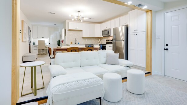 A modern kitchen with white cabinets, a stainless steel refrigerator, and a dining area with a wooden table and chairs. - 2 Mi to Canyon Lake: Cottage w/ Fire Pit & Grill (Canyon Lake)
