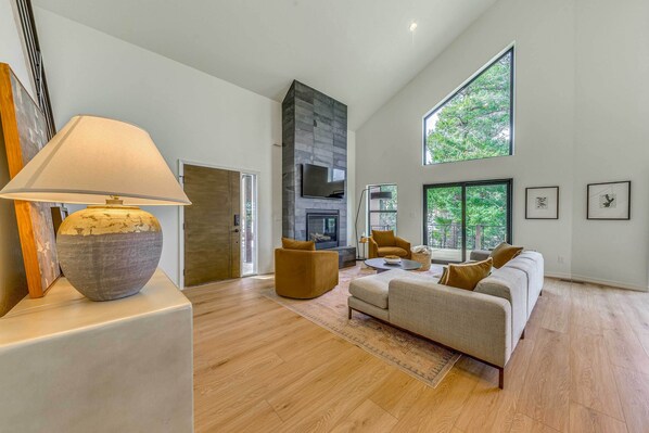 Un salón amplio con chimenea, ventanas grandes y un diseño moderno.