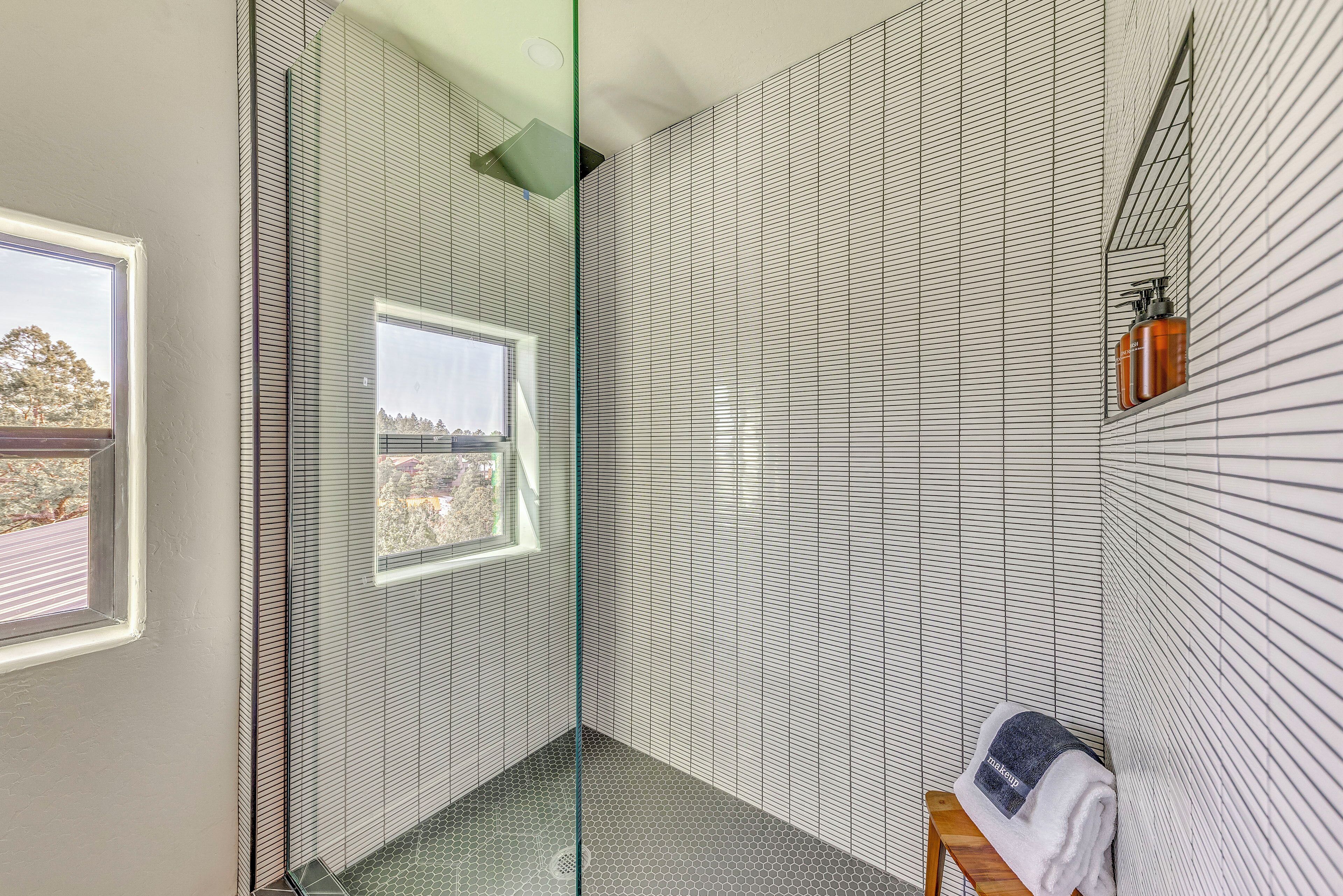 Casa de banho moderna com cabine de duche em vidro, uma pequena janela e um porta-toalhas com uma toalha.