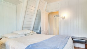 Un dormitorio con cama, mesita de noche, escritorio y una lámpara de pared.