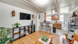 Ein modernes Wohnzimmer mit einem Holzesstisch, einer Couch und einer Küchenzeile im Hintergrund.