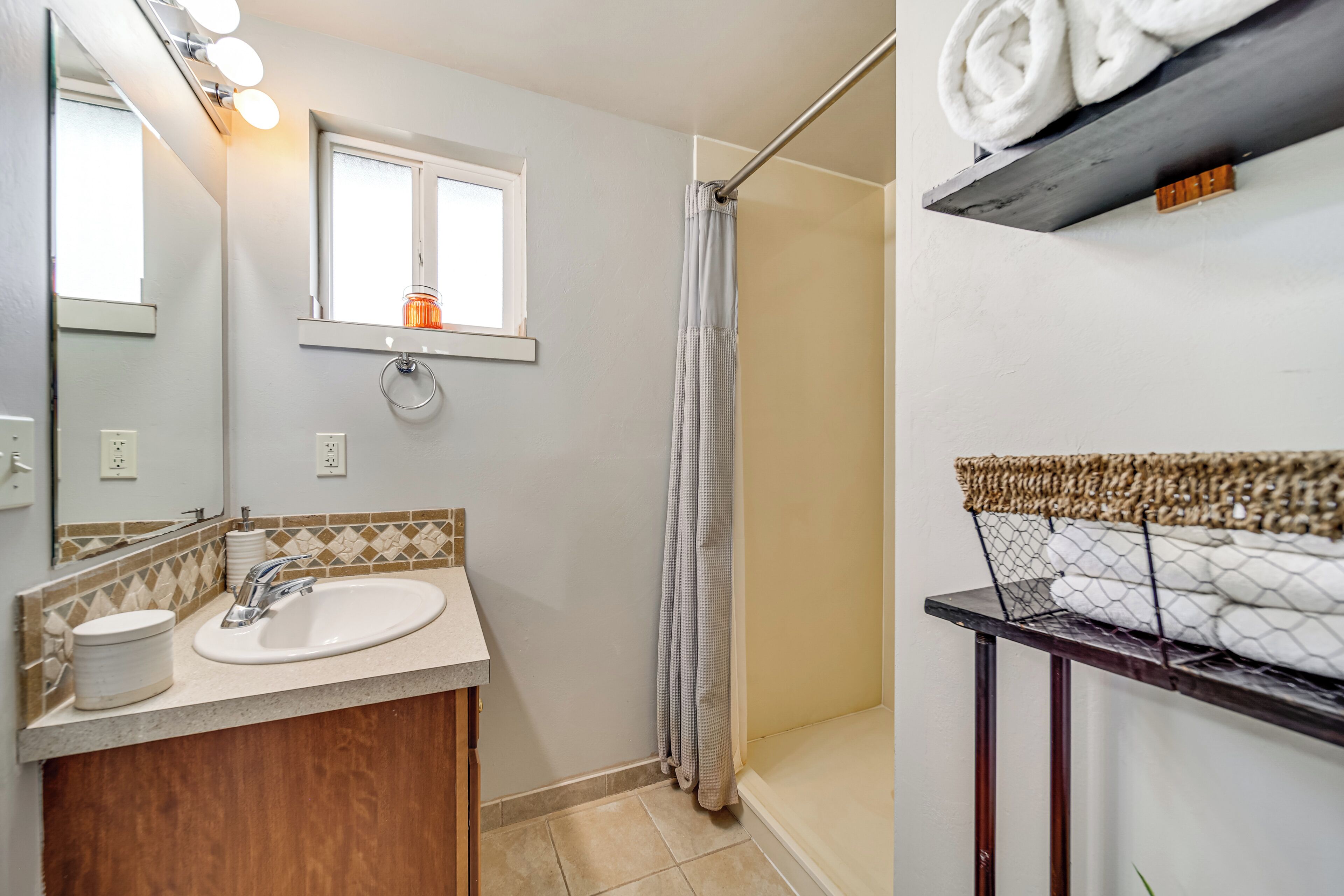 Une salle de bain avec un lavabo, un miroir et un rideau de douche.
