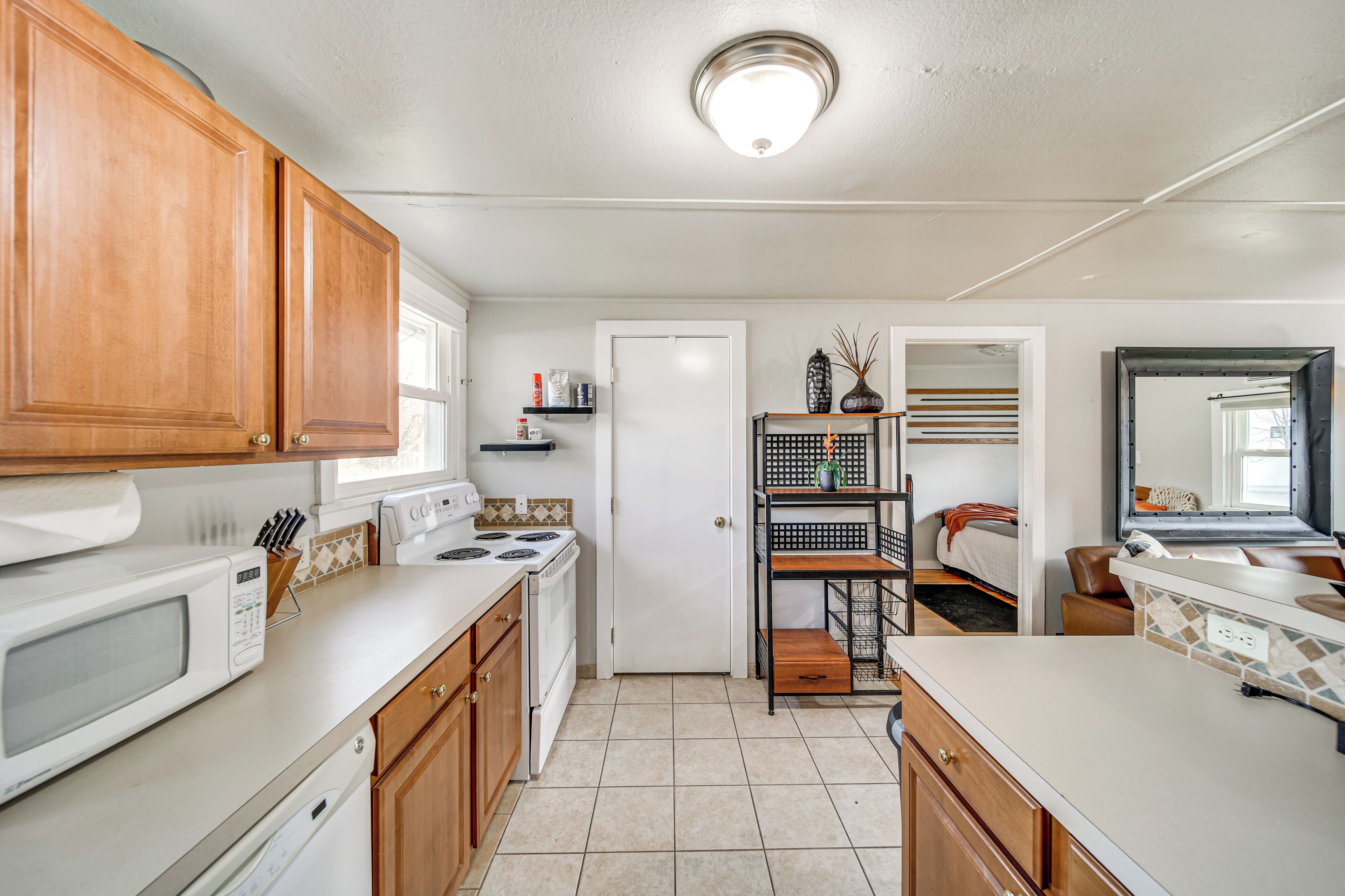 A compact kitchen with wooden cabinets, a microwave, stove, and a small countertop.