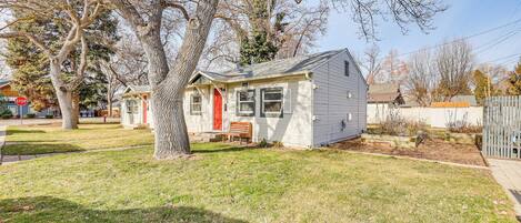 A single-story house with a red front door, a small porch, and a well-maintained lawn.