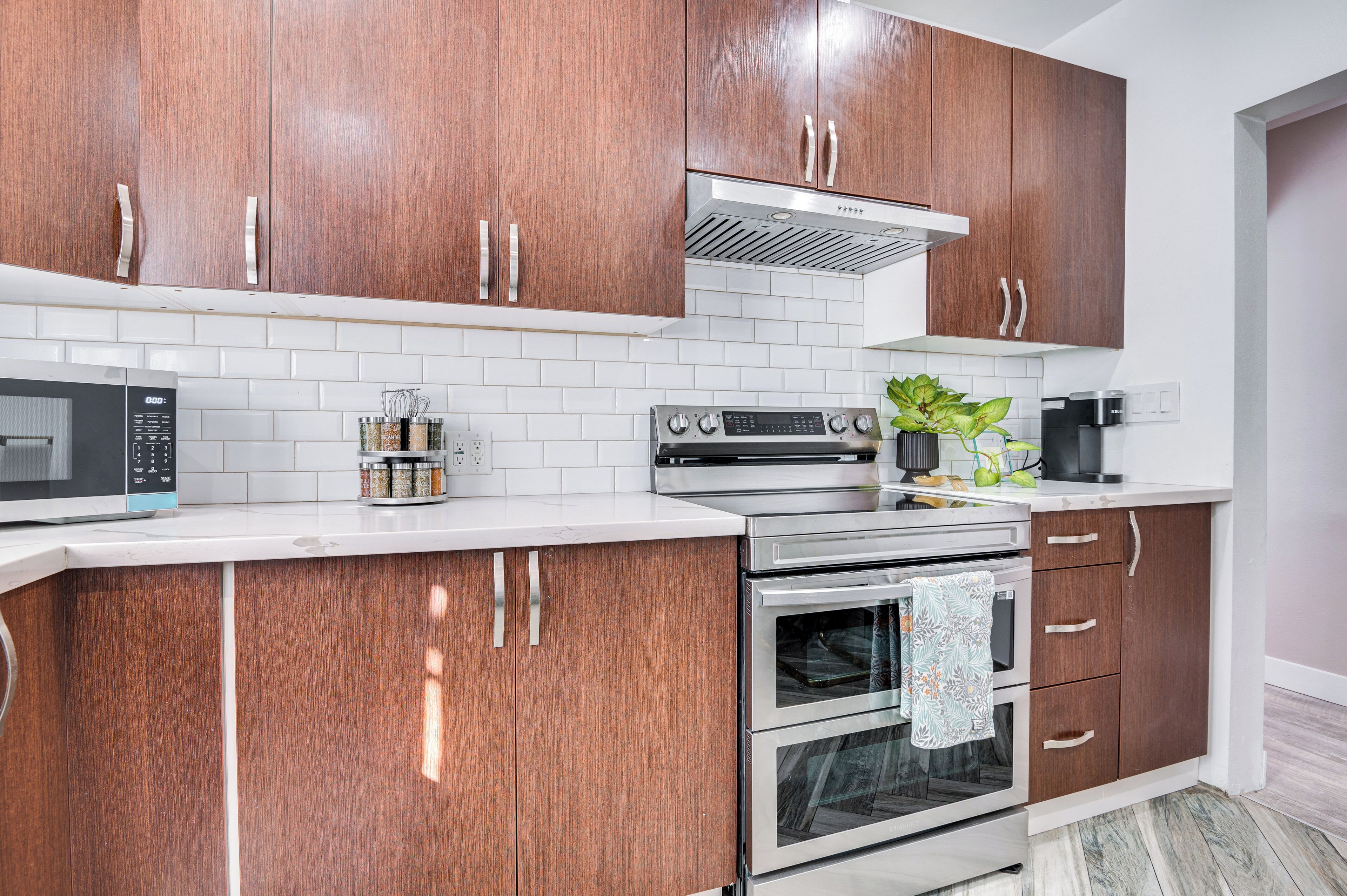 A modern kitchen with wooden cabinets, a stainless steel oven, a microwave, and a coffee maker.