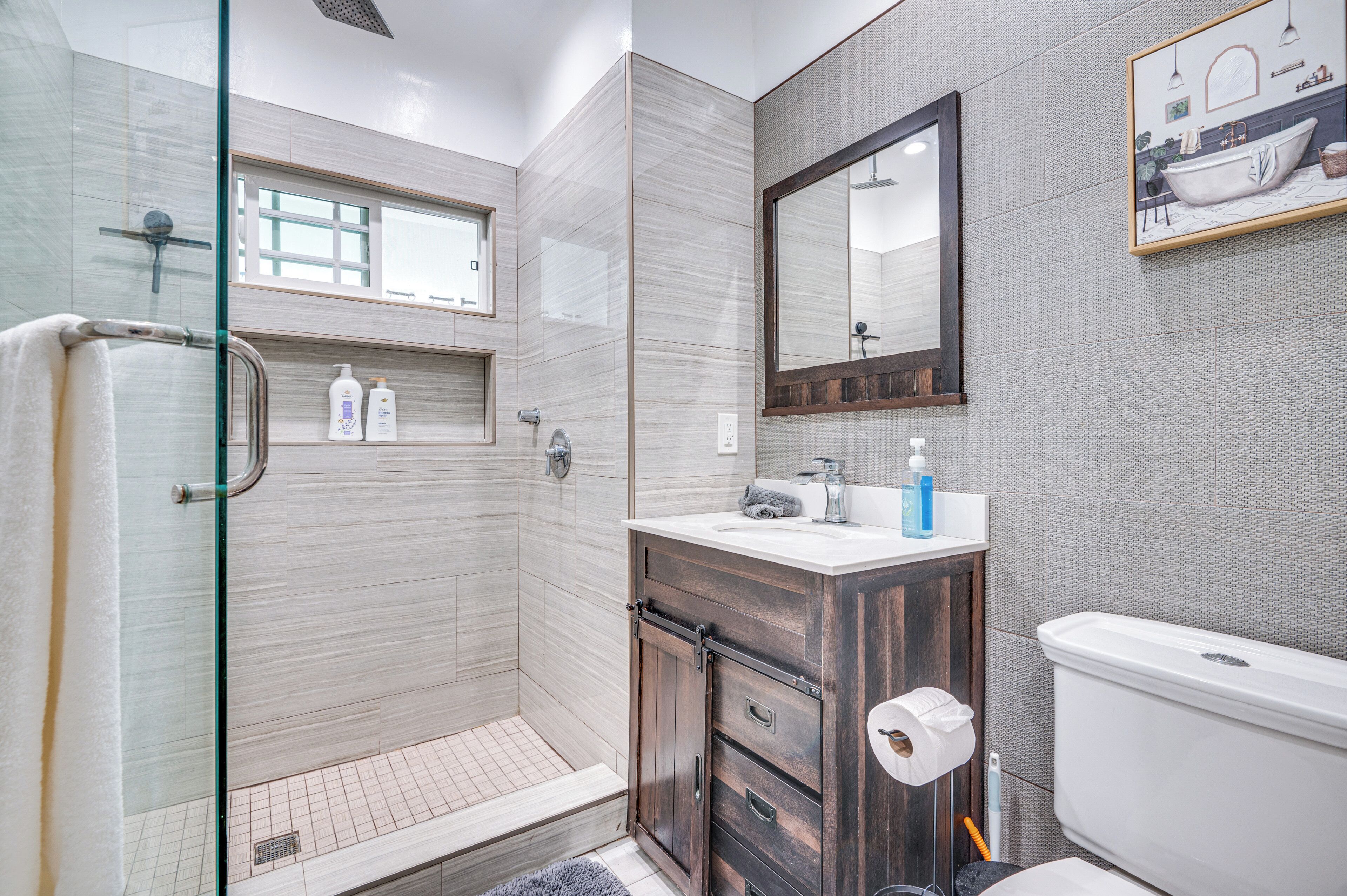 Une salle de bain moderne avec une douche à parois de verre, un meuble-lavabo avec un miroir et des toilettes.