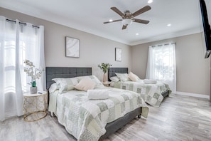 Quarto com duas camas, um ventilador de teto e uma pequena mesa de cabeceira com uma planta.