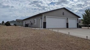 A single-story building with a garage, a driveway, and a gravel area in front. - Charming 3-bedroom house with WiFi, AC minutes from Lake Oahe/ 3 stall garage (Pierre)